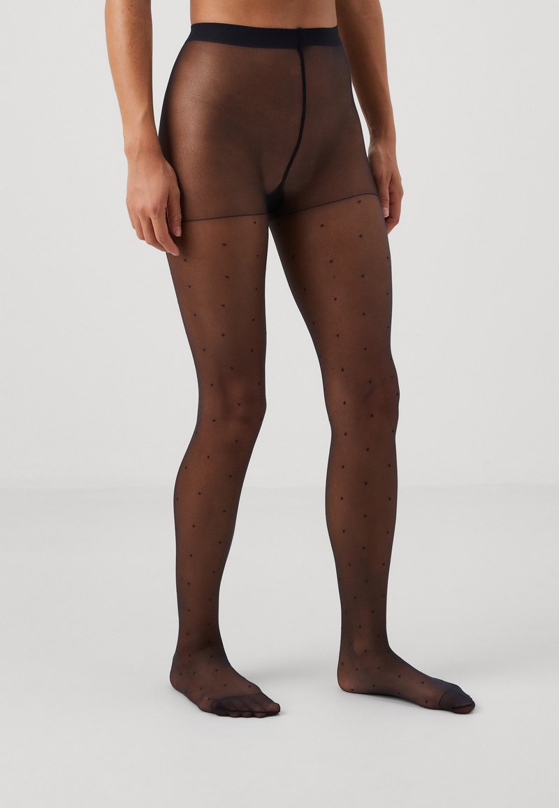 Schwarze transparente Strumpfhosen mit kleinen Pünktchen, die eine glatte Textur und einen breiten Bund haben, der von der Taille bis zum Knöchel reicht.
