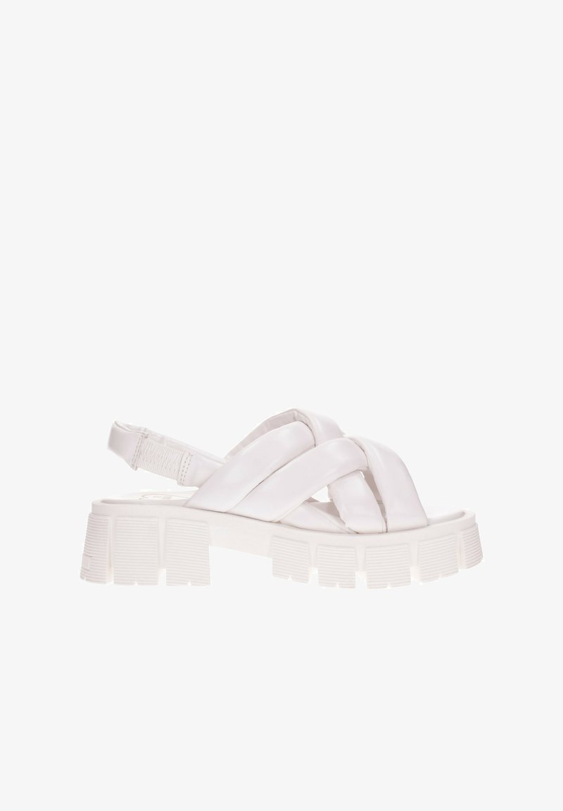 Sandalias planas blancas con una suela gruesa y estriada. Presentan tiras entrecruzadas hechas de material suave y una correa en la parte posterior para mayor soporte.