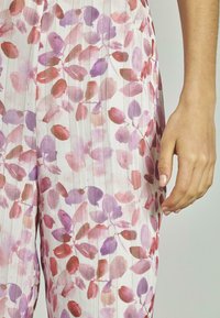 Tissu à motif floral avec des feuilles aquarelles dans des teintes de violet et de rouge, sur un fond clair avec de subtiles rayures verticales.