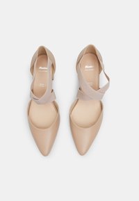 Beige leather shoes with a pointed toe and elastic ankle strap. Smooth texture, minimalistic design, and cushioned insole for comfort.