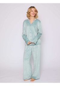 Conjunto de pijama de tejido suave en color verde claro que incluye una camisa abotonada con bolsillo y pantalones de pierna ancha, ambos con una textura lisa y cepillada.