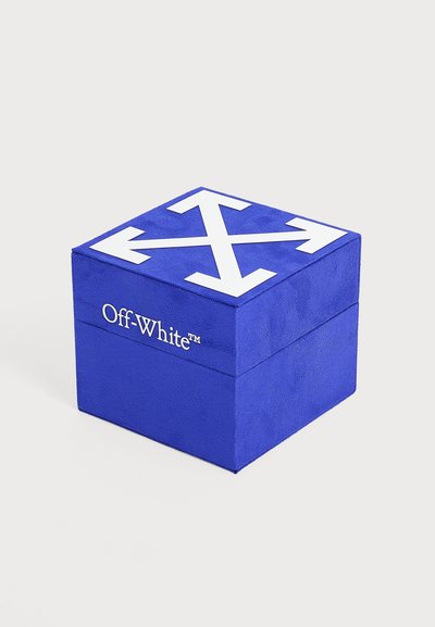Boîte carrée bleue avec des flèches blanches pointant vers l’extérieur en haut et le logo "Off-White" sur le côté, sur un fond clair uni.