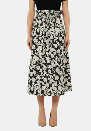 Gonna midi floreale in bianco e nero con vita arricciata e cintura annodata, indossata con tacchi nudi e una maglietta nera.