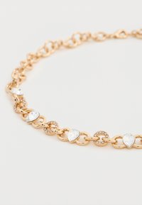 Κολιέ αλυσίδα σε χρυσό τόνο με διαφανείς ριβιόν πέτρες σε σχήμα σταγόνας και στρογγυλές, σχέδιο εναλλασσόμενων κρίκων, λεία υφή και ασφαλές κούμπωμα.