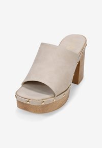 Sandalias de plataforma beige con un diseño de punta abierta y ancha, material de imitación de ante, tacón de madera y acentos de tachuelas doradas alrededor de la suela.