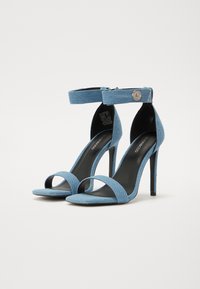 Mėlynos džinsinės aukštakulnės šlepetės su vienu priekiu dirželiu, kulkšnies dirželiu su spaudiniu ir elegantišku stiletto kulnu.