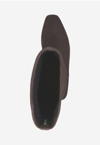 Bottine en suède marron avec un bout pointu, une texture lisse et une forme ajustée, dotée d'une doublure intérieure douce et de accents minimalistes.