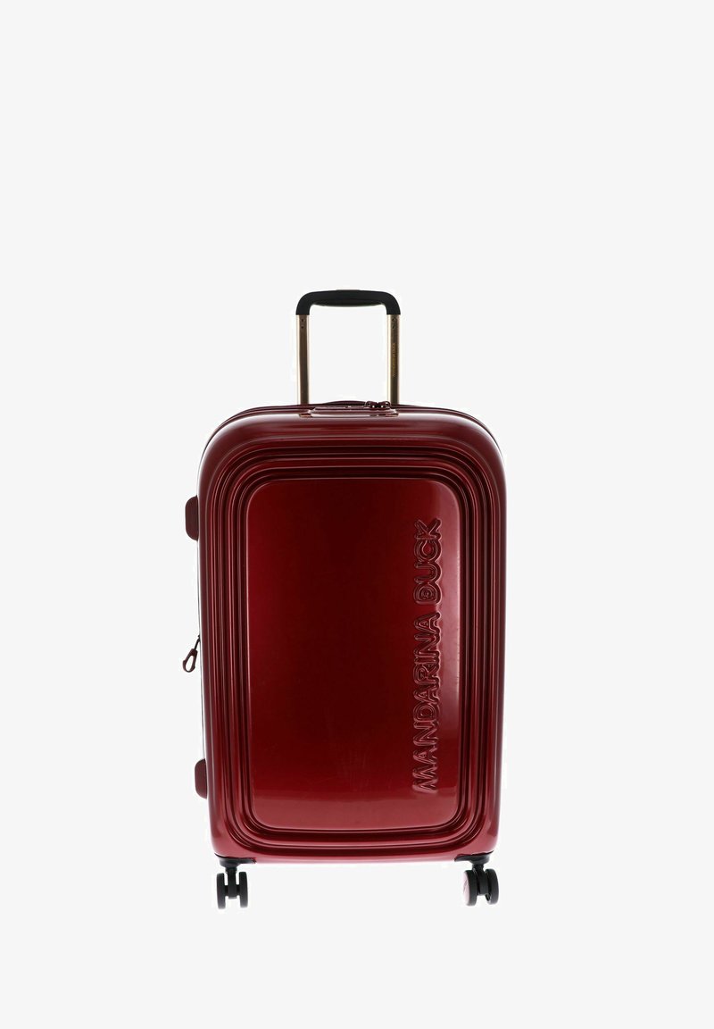 Valise rigide rouge avec un design strié, poignée noire télescopique et quatre roues. Présente un logo embossé à l'avant.