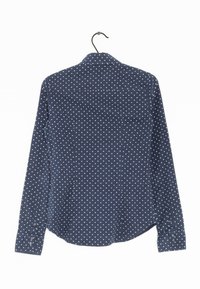 Chemise bleu marine à boutons avec des pois blancs, à manches longues, avec un col et des poignets à double bouton. Fabriquée en tissu texturé.