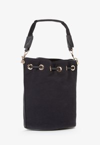 Sac seau noir en toile avec œillets dorés et fermeture à cordon, présentant une poignée texturée noire et une forme rectangulaire structurée.