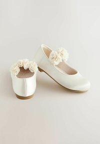 Chaussures de ballet en satin blanc avec un bout rond, présentant une texture de tissu doux et des accents floraux sur le dessus. Semelle plate, détails minimalistes.