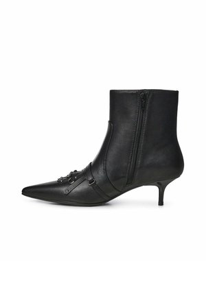 Stivaletto in pelle nera con punta appuntita, zip laterale, tacco basso a stiletto e cinturino decorativo con inserti metallici sulla parte frontale.