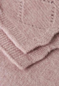 Mjuk rosa stickad tyg med en strukturerad yta, som har tre överlappande lager som visar ett fluffigt, varmt ull-liknande material.