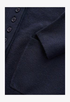 Cardigan en tricot bleu marine avec un tissu texturé, six boutons et une poche avant avec des poignets côtelés.