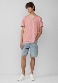 Rood en wit gestreept t-shirt met korte mouwen en v-hals, gecombineerd met lichtblauwe denimshorts en witte sneakers. Eenvoudig ontwerp, relaxte pasvorm.
