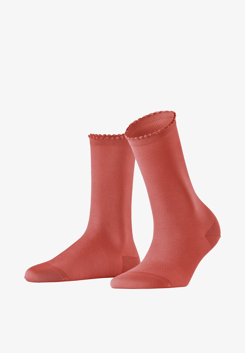 Chaussettes corail avec un revers à côtes en forme de vagues, présentant un motif texturé de points en relief sur une surface lisse. Design à longueur de cheville.