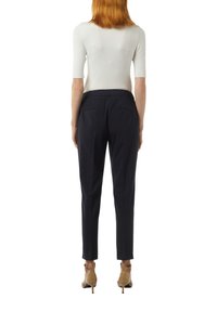 Schwarze Nadelstreifen-Hosen mit schmal zulaufendem Bein, gefertigt aus einem leichten Stoff; besitzt zwei Gesäßtaschen und einen mittelhohen Bund.