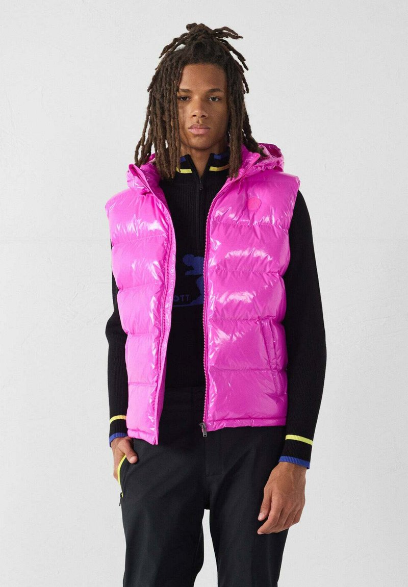 Gilet imbottito lucido di colore rosa acceso con cappuccio, caratterizzato da sezioni trapuntate e cerniera frontale. Indossato sopra una maglia nera a maniche lunghe.