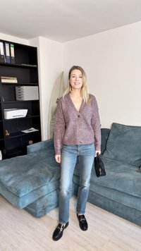 Cardigan en tricot bordeaux avec un col en V et une fermeture à boutons, porté sur un jean bleu clair. Des chaussures noires et un petit sac noir complètent l'ensemble.