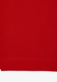 Röd tyg med en texturerad, vävd yta. Horisontell sömnad längs den nedre kanten. Slät yta med en jämn färg.