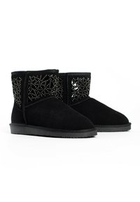 Botas de tobillo de ante negro con una textura suave, que presentan un patrón decorativo de cuentas en los laterales y una sólida suela de goma negra.
