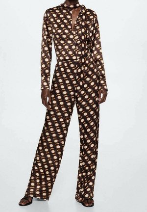 Langærmet jumpsuit i brunt stof med et geometrisk mønster i nuancer af beige og creme, med krave og taljebånd.