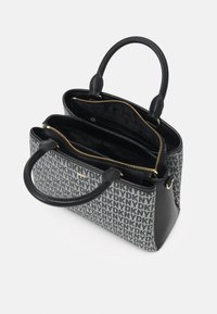 Sac à main DKNY noir et gris avec doubles poignées, deux compartiments zippés et poches intérieures sur fond blanc.