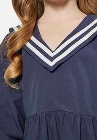 Merenneito puuvillamekko, jossa on V-kaula-aukko ja valkoiset raidat, pehmeä rakenne ja kerätty vyötärölinja.