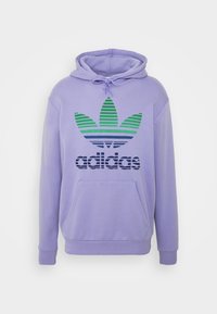 Lila hoodie med känguruficka framtill och en grafisk logotyp med gröna och blå randiga detaljer. Blandning av bomull.