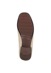 Beige leren schoen met een gladde bovenkant, voorzien van een bruine rubberen zool en een textuurpatroon. Inclusief ingezonken branding en een rode accent.