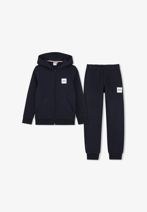 Marineblauwe zip-up hoodie en bijpassende joggingbroek met BOSS-logo patches op borst en dij, plat neergelegd op een witte achtergrond.