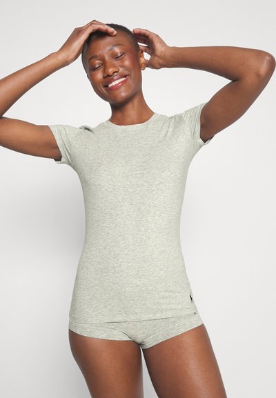 Sivý priliehavý tričko s krátkymi rukávmi, vyrobené z jemného, hladkého materiálu. Má okrúhly výstrih a nenápadné logo značky blízko lemovania.