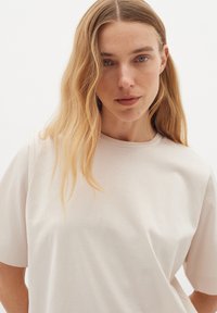 Ljusbeige kortärmad t-shirt med rund halsringning, gjord av mjukt bomullstyg, med en avslappnad passform och minimal textur.