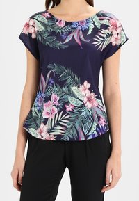 Marinblommig blus med korta ärmar, rundad halsringning och ett tropiskt mönster i rosa och gröna nyanser. Mjuk tyg med avslappnad passform.