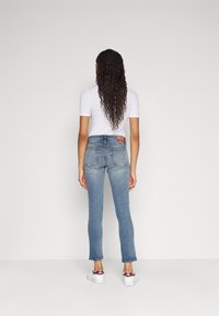 Granatowe, wąskie dżinsy z wysokim stanem, z wyblakłą fakturą i kontrastowym przeszyciem. Posiadają tylne kieszenie oraz skórzaną naszywkę z logo.