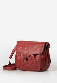 Borsa a tracolla rossa in pelle con patta pieghevole, hardware nero, tracolla regolabile e finitura texture. Forma morbida e arrotondata con pieghe.