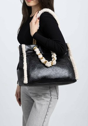 Bolso tote de cuero negro con acentos texturizados en crema y asas de cadena trenzada. Cuenta con herrajes en tono dorado y un diseño de apertura superior.