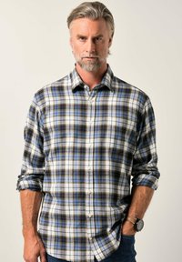 Camicia a quadri caratterizzata da colori blu, bianco e marrone, realizzata in tessuto morbido, con maniche arrotolabili e chiusura a bottoni.