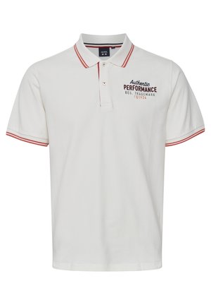 Valge polo särk, millel on kaelus, lühikesed varrukad, punased aktsendid kaelusel ja varrukatel, rinnal on tikandiga "Authenic Performance".