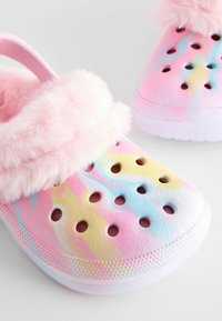 Sabots en feutre rose avec un motif pastel marbré, dotés de trous pour la ventilation et de surfaces texturées sur une semelle blanche.
