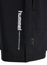 Short de sport noir avec le logo blanc « hummel PERFORMANCE » imprimé verticalement près de l'ourlet et une petite étiquette chevron sur la couture latérale.