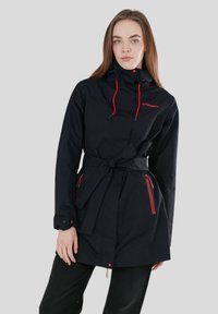 Giacca impermeabile nera con cintura in vita, lacci rossi, due tasche con zip e cappuccio. Ha una texture liscia e elegante.