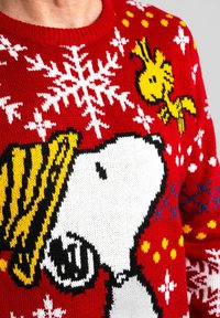 Maglione di Natale rosso con grandi fiocchi di neve bianchi, Snoopy che indossa un cappello giallo e Woodstock in giallo nella zona del petto.