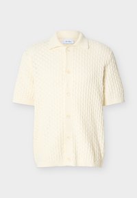 Krēmkrāsas īsroku adīta kardigāna ar fakturētu rakstu, ribota apkakle, poga priekšpusē un ribotas apmales maliņa un aproces.