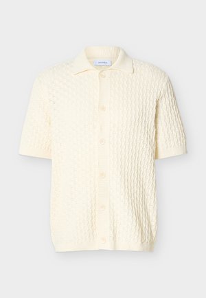 Cardigan corto a maniche corte color crema in maglia con motivo testurizzato, collo a coste, apertura frontale con bottoni e orlo e polsini a coste.