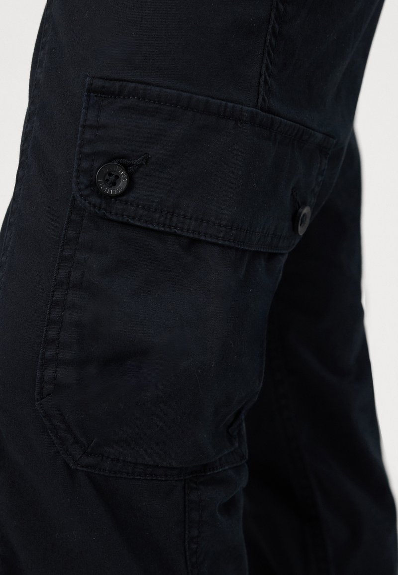 Schwarze Cargo-Hosen aus strukturiertem Stoff, mit einer Seitenasche mit Knopfverschluss und sichtbaren Nähten.