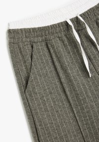 Grijze gestreepte sweatpants met een elastische witte tailleband, trekkoordsluiting en zijzakken, gemaakt van zachte, gestructureerde stof.