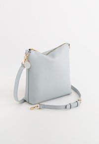 Vaaleansininen synteettinen käsilaukku, jossa on kolmion muotoinen muotoilu, kullattu vetoketju, säädettävä olkahihna ja pyöreä koriste.