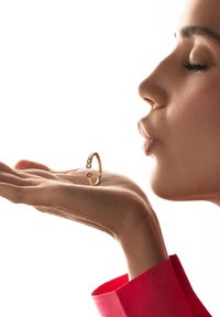 Anillo de oro con una banda texturizada que presenta una joya rosa y múltiples piedras claras, mostrado sobre una mano en perfil lateral.