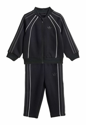 Czarny dres dziecięcy Adidas z kurtką na zamek i spodniami, ozdobiony białym obszyciem i charakterystycznymi trzema paskami na rękawach i nogawkach.